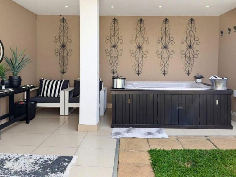 Covered patio area featuring a built-in spa, tiled flooring, and recessed lighting, providing a comfortable space for outdoor relaxation.