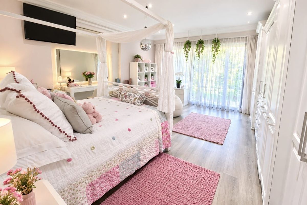 Spacious bedroom featuring light laminate flooring, extensive built-in wardrobe storage, recessed lighting, and large sliding glass doors providing ample natural light.