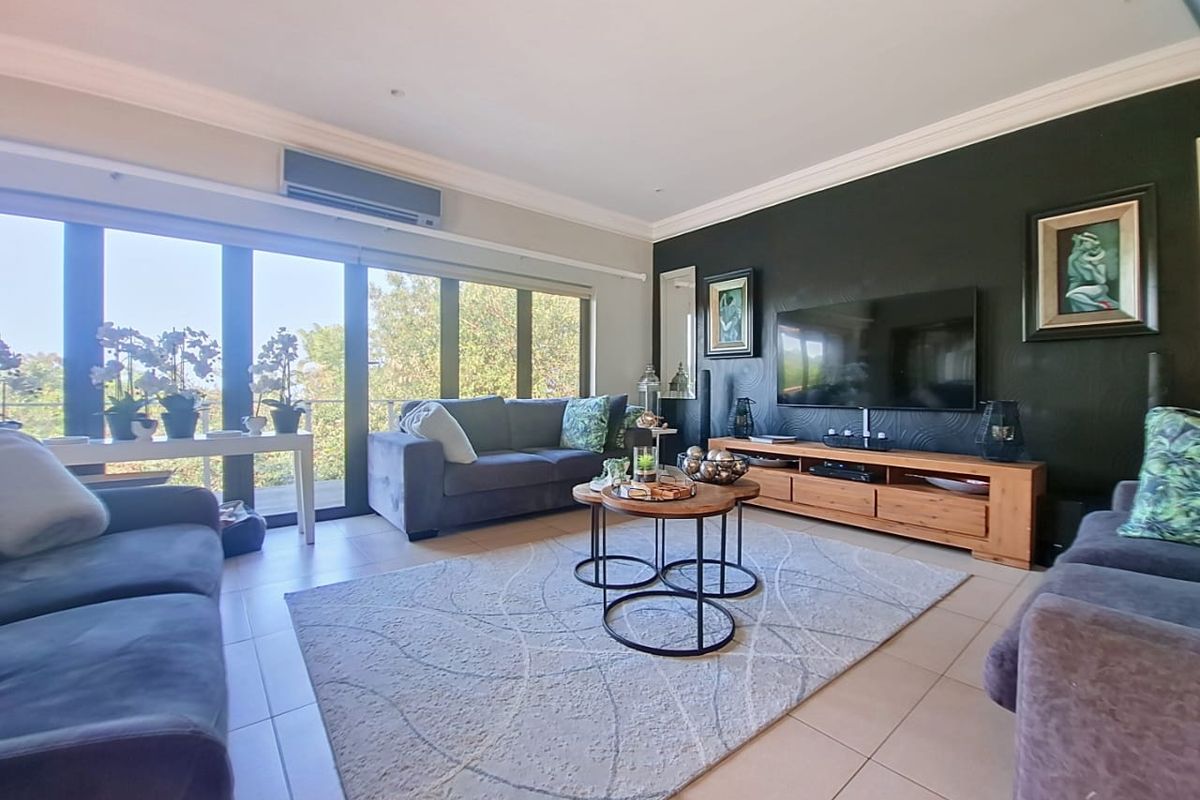A well-maintained living room featuring tiled flooring, a split-system air conditioner, and large sliding glass doors that provide ample natural light.