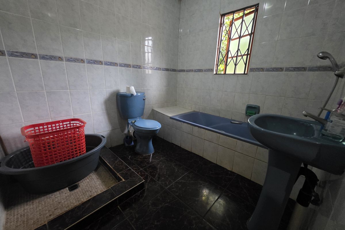 A dated bathroom featuring blue sanitaryware, tiled walls and flooring, and a built-in bathtub, offering significant potential for a modern renovation.