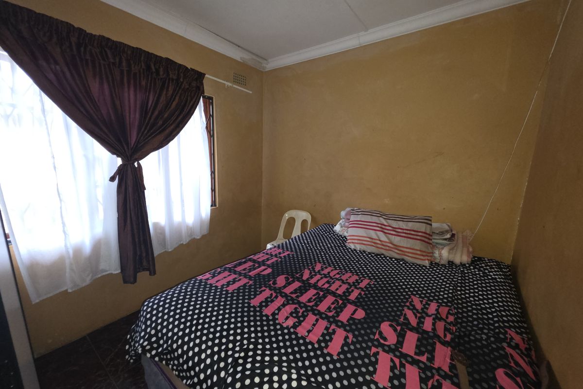 A bedroom featuring tiled flooring and cornice detailing, currently requiring cosmetic updates to the wall finishes to improve the overall aesthetic.