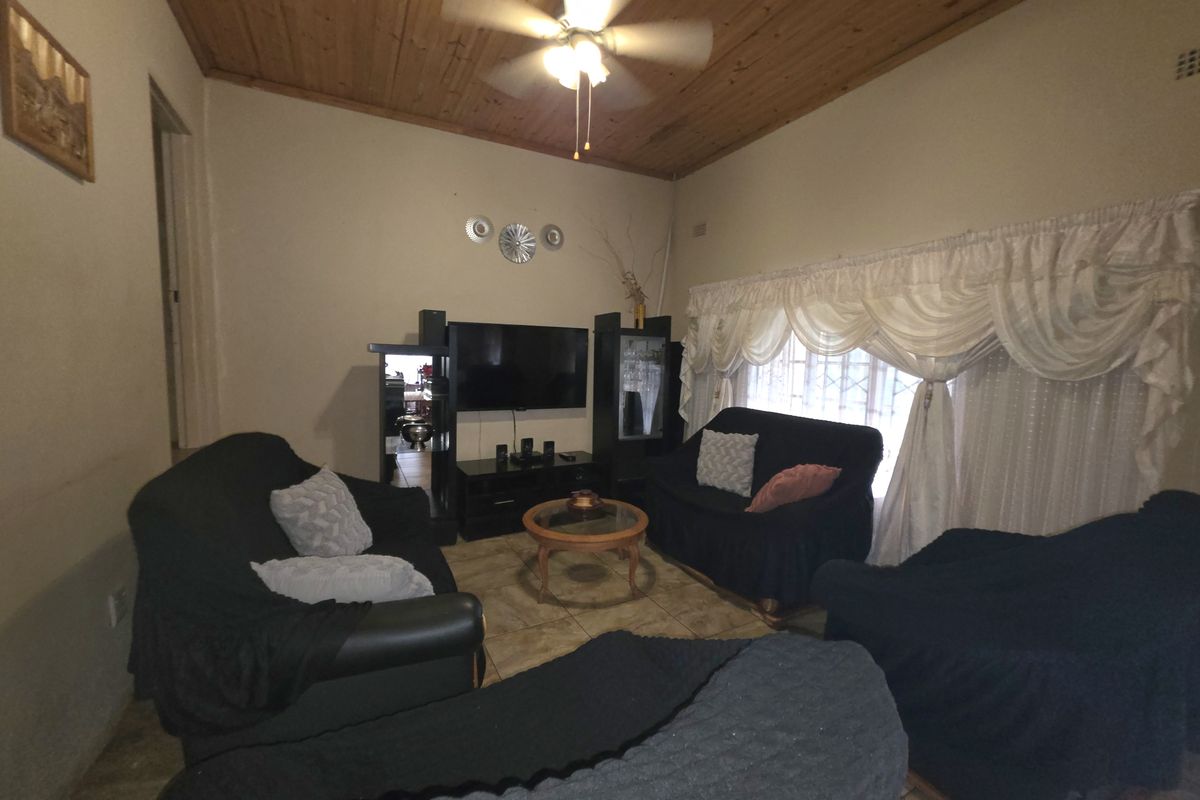A living room featuring a timber ceiling, ceiling fan, and tiled flooring, providing a functional space for relaxation.