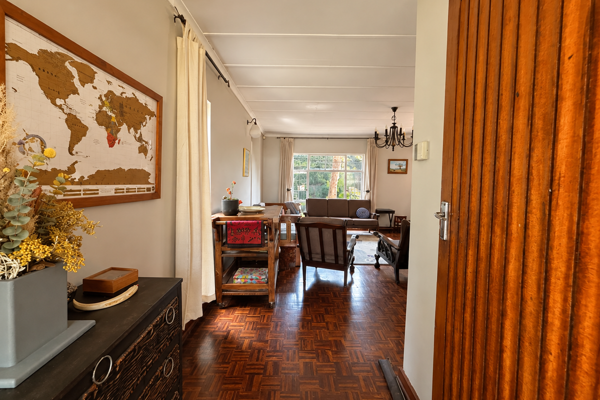 A view from the entrance into a bright living area featuring classic parquet flooring, large windows, and a warm, inviting atmosphere.