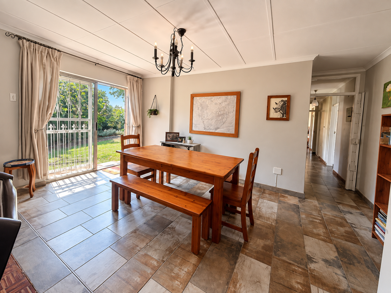 Bright dining room featuring tiled flooring, a chandelier, and a sliding glass door providing direct access to the garden.