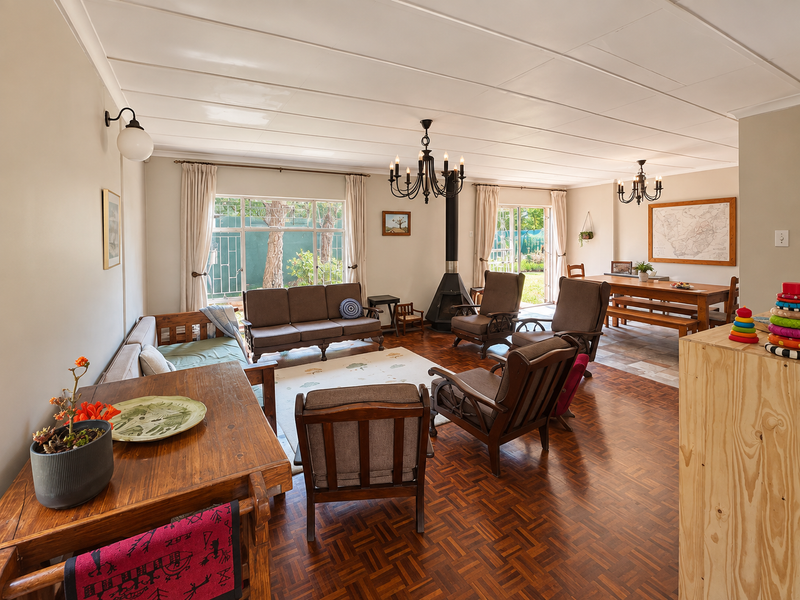 Spacious open-plan living and dining area featuring classic parquet flooring, a central freestanding fireplace, and direct access to the garden through sliding glass doors.