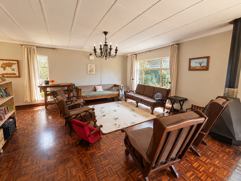 Spacious living room featuring classic parquet flooring, a prominent freestanding fireplace, and a wrought iron chandelier, offering a warm and inviting atmosphere.