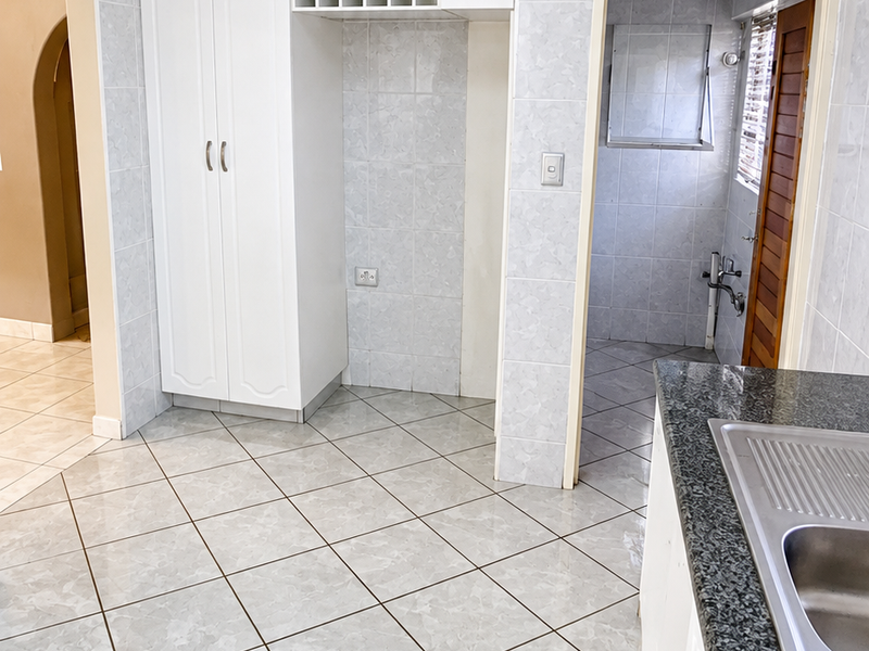 A clean, tiled kitchen area featuring built-in white cabinetry, granite countertops, a stainless steel sink, and a dedicated wine rack storage space.