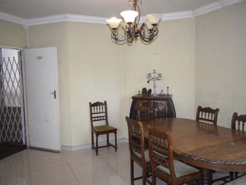 Dining area featuring tiled flooring, decorative ceiling cornice, and a classic chandelier, providing a functional space for meals.