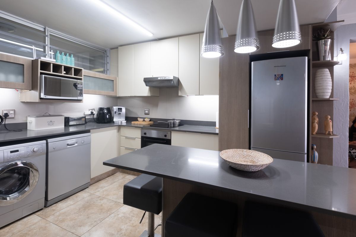 Modern kitchen featuring sleek cabinetry, stone countertops, integrated appliances, and a functional breakfast bar with contemporary pendant lighting.