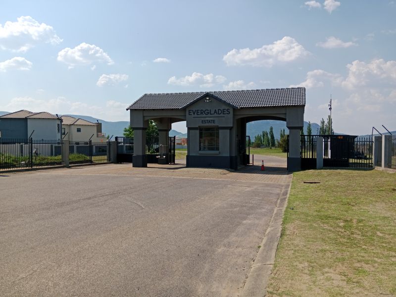 The main entrance gatehouse of Everglades Estate, featuring a paved driveway, secure perimeter fencing, and a well-maintained structure.