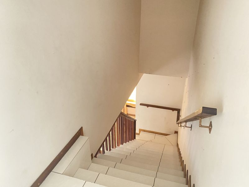 A functional staircase featuring tiled steps, a wooden handrail, and a wooden balustrade, connecting different levels of the home.