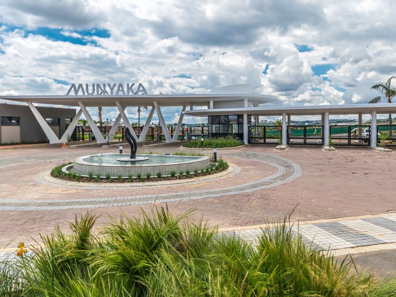 The main entrance to the Munyaka estate features a modern architectural canopy, a circular paved driveway, and a central water fountain.