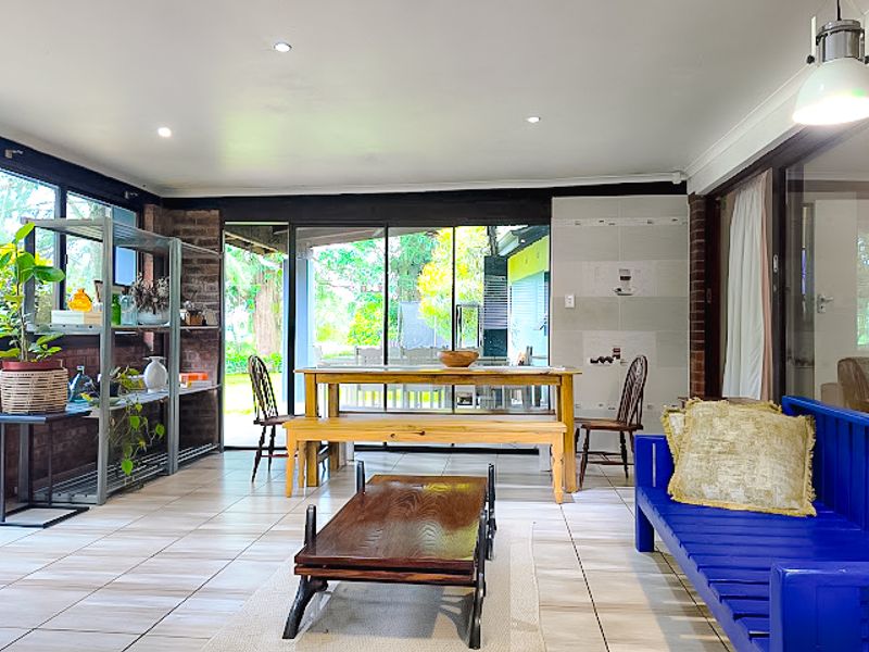 Spacious open-plan living area featuring tiled flooring, exposed brick walls, and large sliding glass doors that provide seamless access to the outdoor space.