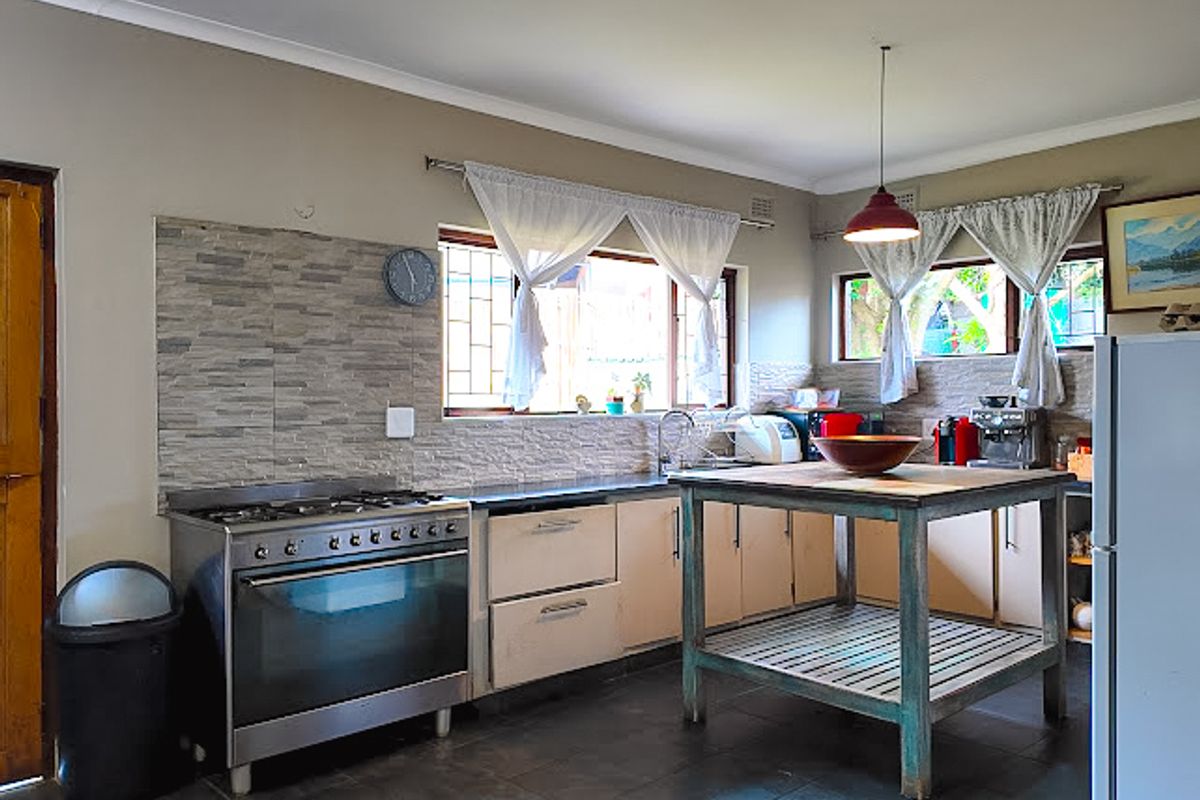 A functional kitchen featuring a gas stove, stone-look splashback, built-in cabinetry, and tiled flooring, offering a practical layout for daily cooking.