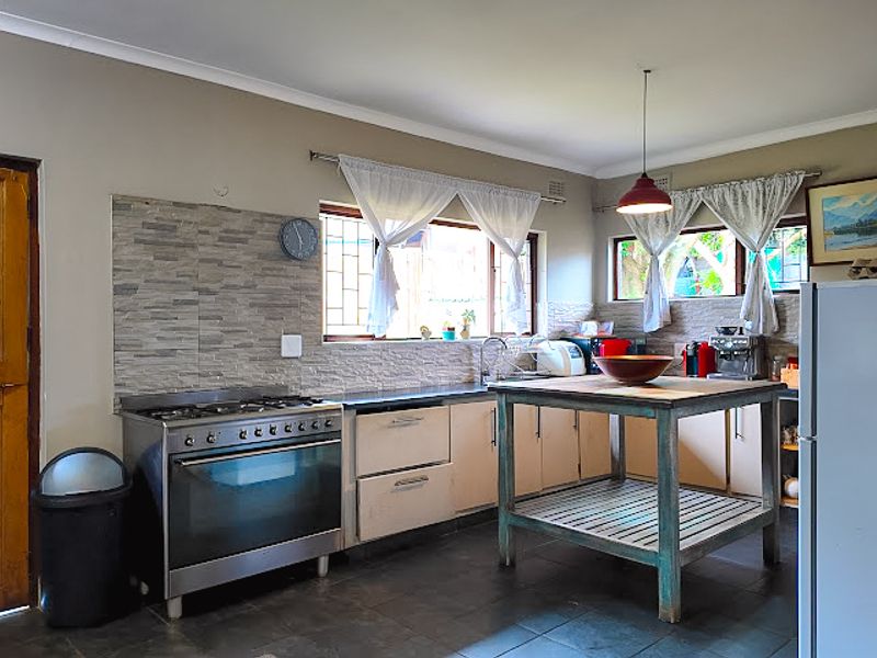 A functional kitchen featuring a gas stove, stone-look splashback, built-in cabinetry, and tiled flooring, offering a practical layout for daily cooking.