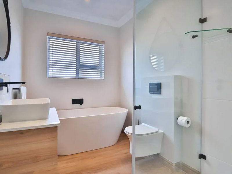 Modern bathroom featuring a sleek freestanding bathtub, wall-mounted toilet, glass shower enclosure, and a contemporary vanity with a vessel sink.