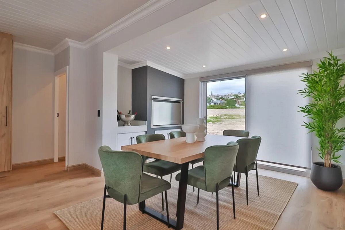 Modern living area featuring timber flooring, a built-in braai, recessed lighting, and a sliding glass door providing natural light and outdoor access.
