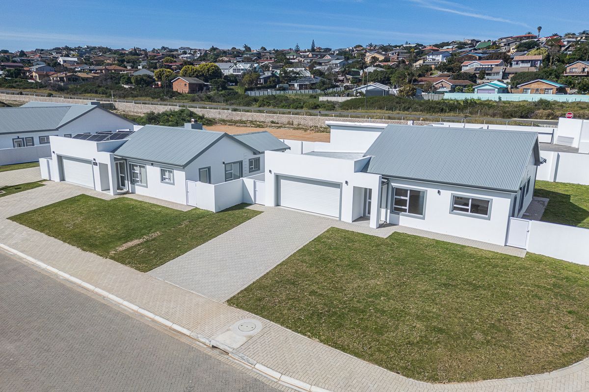Aerial view of modern residential houses featuring paved driveways, garages, solar panels, and well-maintained lawns in a suburban estate setting.