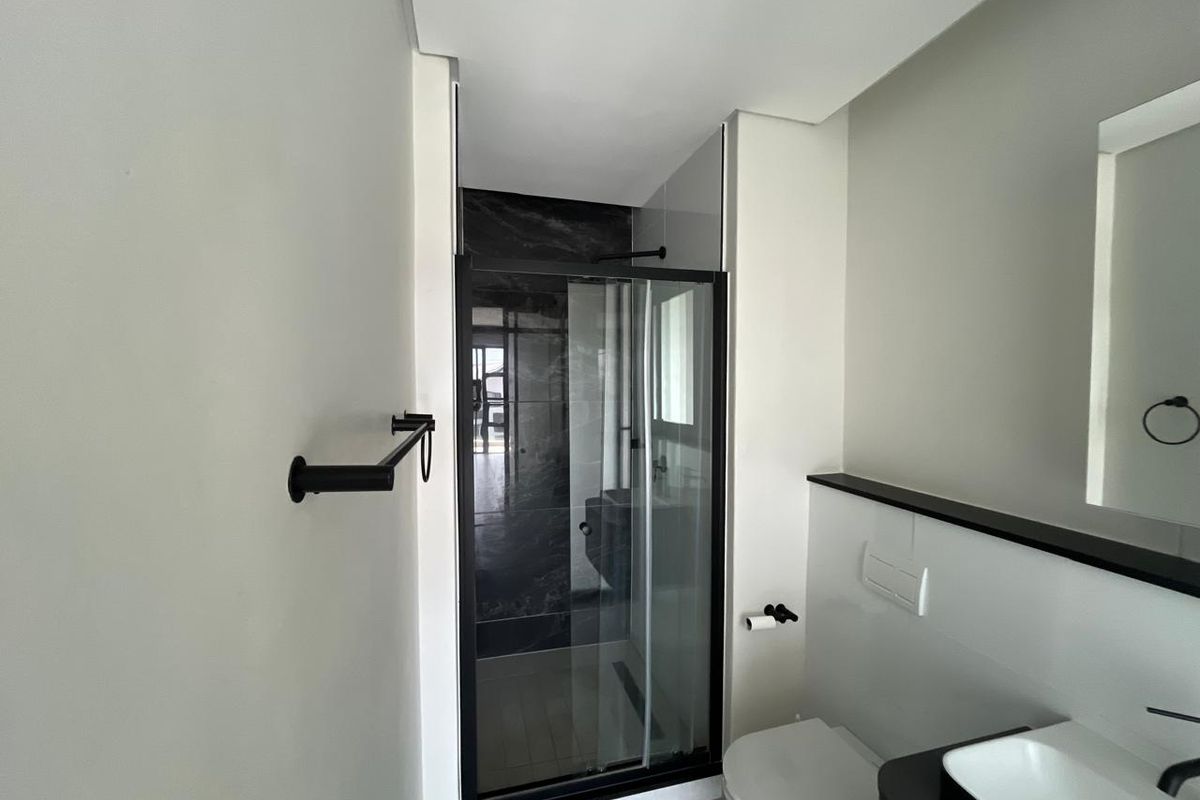Modern bathroom featuring a walk-in shower with black-framed glass, wall-mounted toilet, and sleek vanity with contemporary black fixtures.
