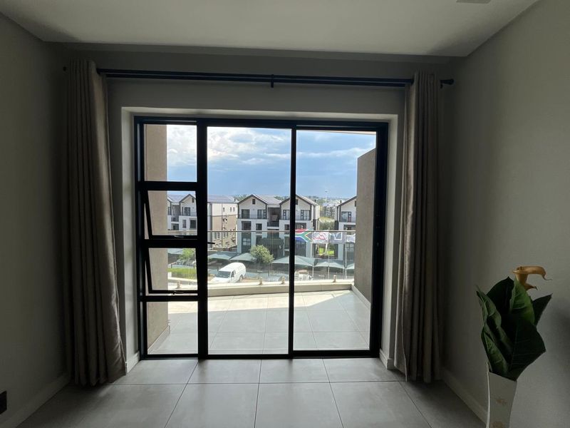 Bright living area featuring large sliding glass doors that open onto a private balcony with modern tiled flooring.