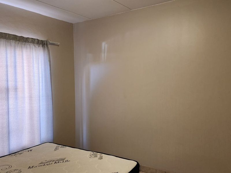 A simple bedroom interior featuring neutral wall finishes and a curtain rail, providing a blank canvas for personalization.