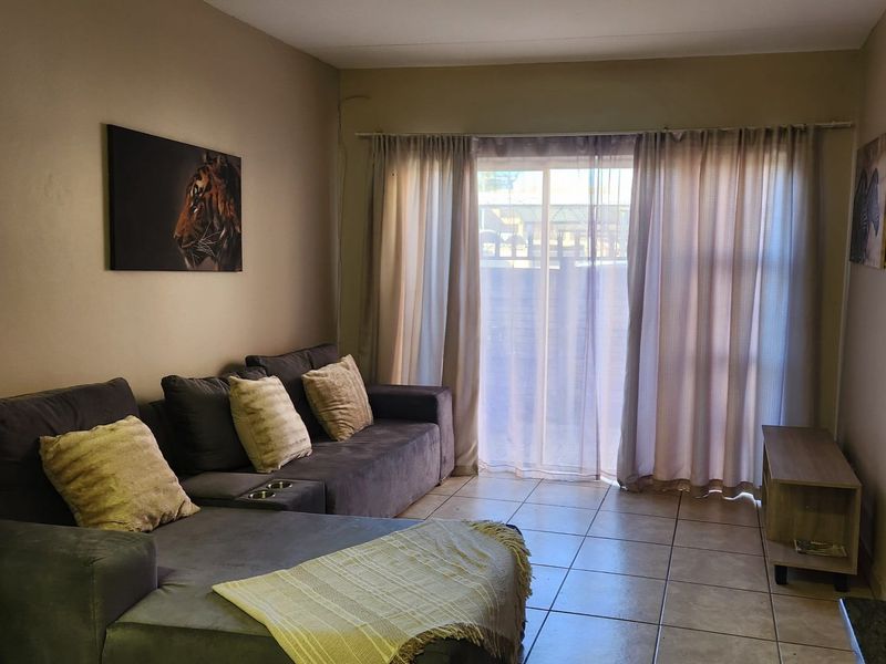 A living room featuring tiled flooring and a sliding glass door providing access to the exterior.