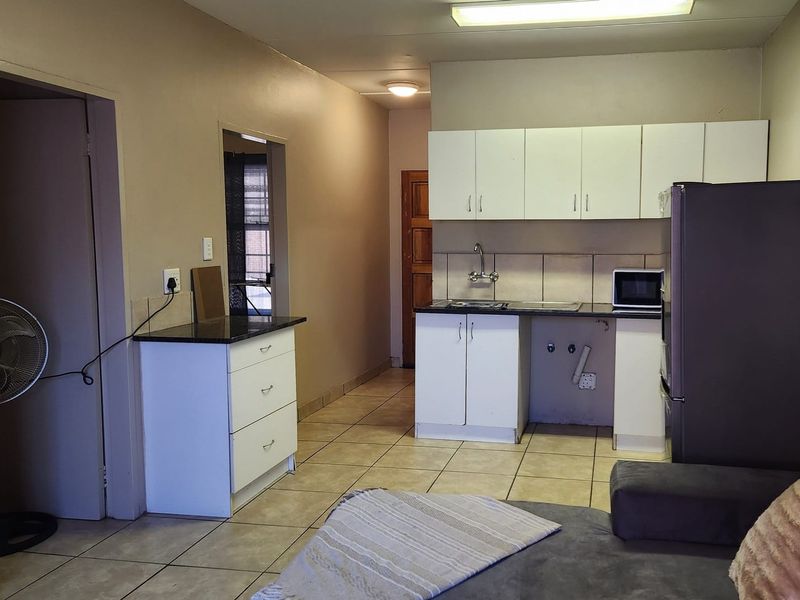 Open plan kitchen area featuring tiled flooring, white cabinetry, and granite countertops, requiring minor repairs to cabinetry and plumbing fixtures.