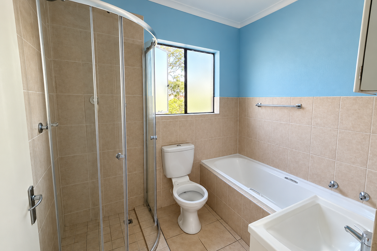 A clean, functional bathroom featuring a separate shower enclosure, bathtub, toilet, and vanity basin with neutral wall and floor tiling.