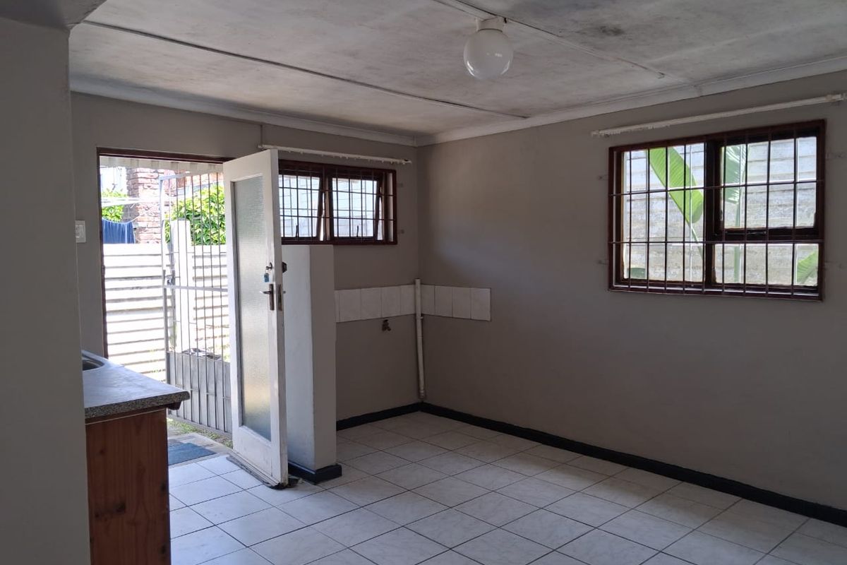 A functional kitchen area featuring tiled flooring, built-in cabinetry, and direct access to the exterior through a security-gated door.