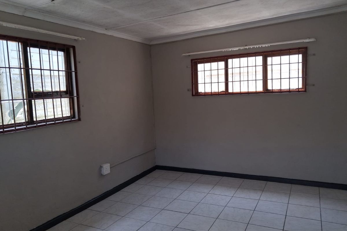 An empty bedroom featuring tiled flooring, security bars on the windows, and a neutral wall finish, ready for personalization.
