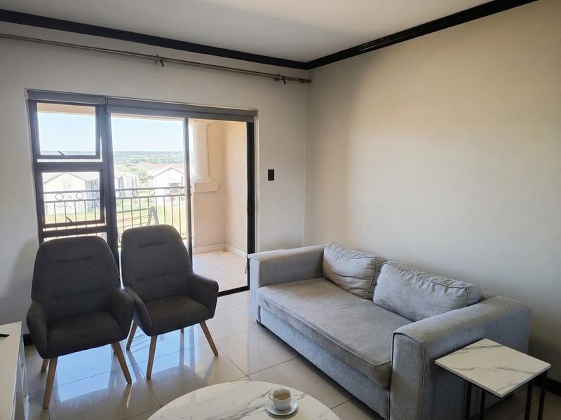 A bright living room featuring tiled flooring and a large sliding glass door that provides direct access to an outdoor balcony.