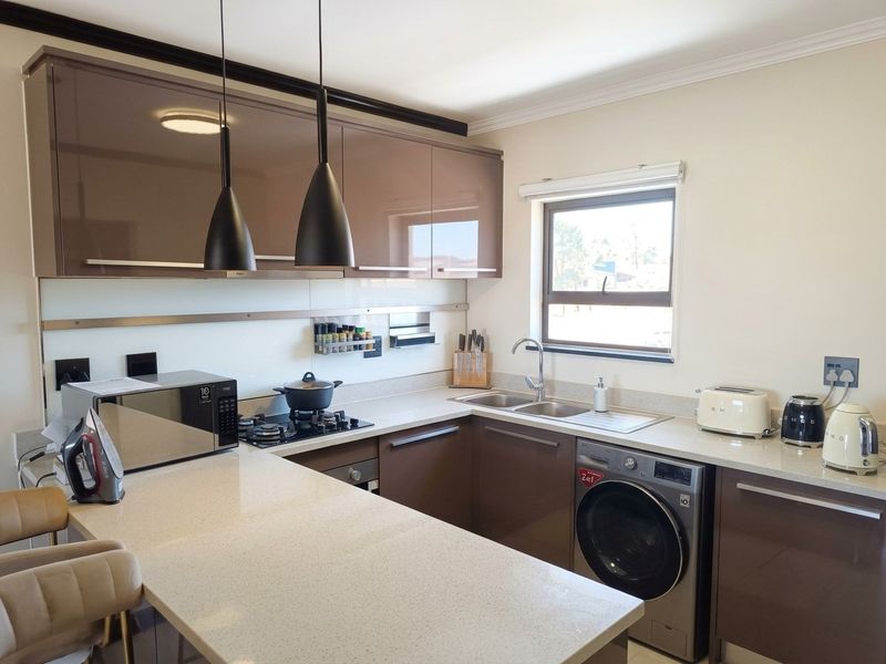 Modern kitchen featuring high-gloss cabinetry, stone countertops, integrated gas hob, built-in oven, and a convenient built-in washing machine.