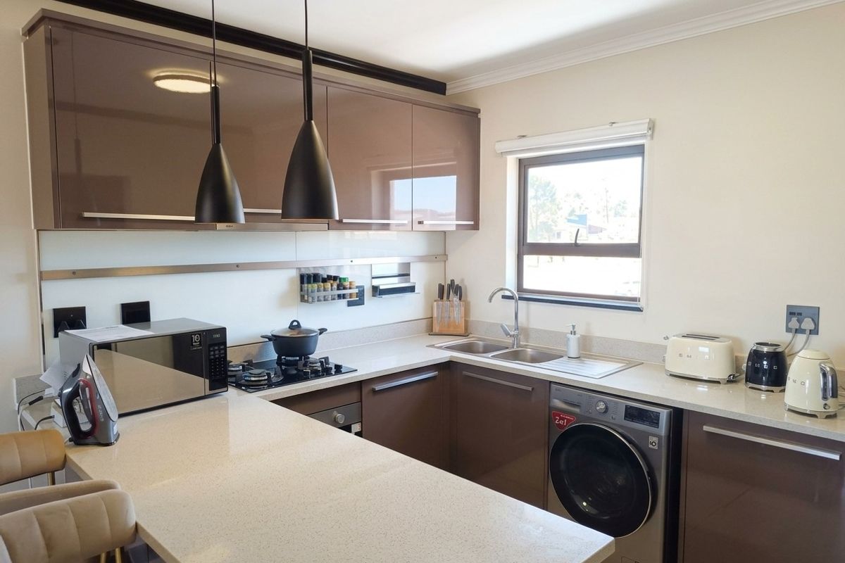 Modern kitchen featuring high-gloss cabinetry, stone countertops, integrated gas hob, built-in oven, and a convenient built-in washing machine.