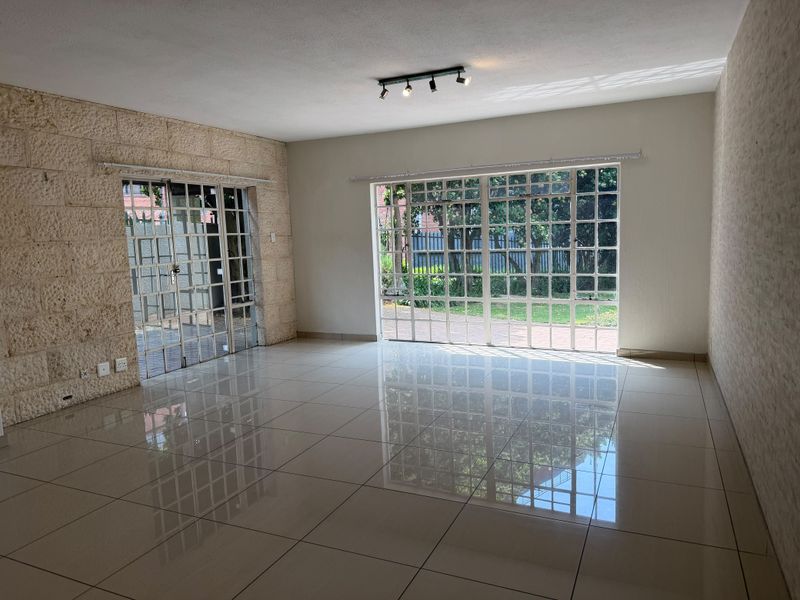Spacious, light-filled living area featuring polished tile flooring, a textured stone feature wall, and large glass doors opening to the garden.