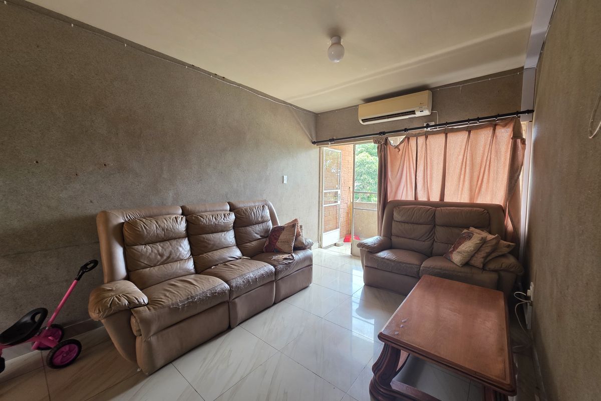 Living room featuring tiled flooring, a wall-mounted air conditioning unit, and direct access to an outdoor balcony area.