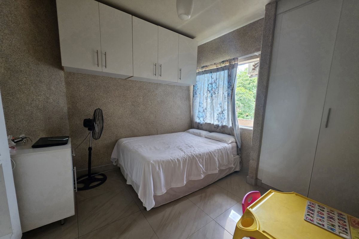 A compact bedroom featuring tiled flooring, built-in overhead cupboards, and a built-in wardrobe, providing functional storage space.