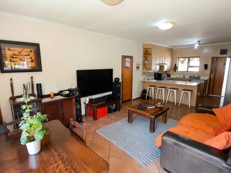 Open-plan living and dining area featuring a functional kitchen with breakfast bar, tiled flooring, and integrated cabinetry.