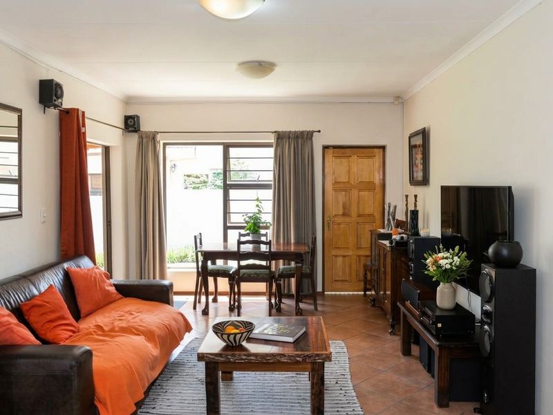 An open-plan living and dining area featuring tiled flooring, a sliding glass door providing natural light, and a traditional wooden door.