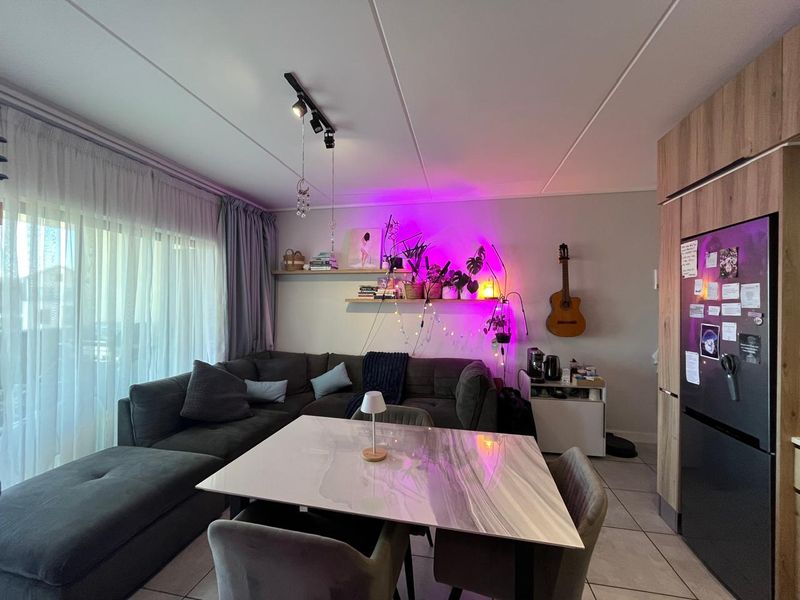 An open-plan living and dining area featuring tiled flooring, modern track lighting, and integrated cabinetry, creating a functional and connected living space.