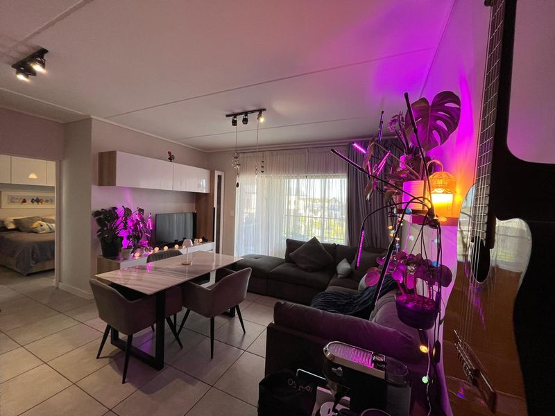 An open-plan living and dining area featuring tiled flooring, built-in cabinetry, and direct access to a balcony through sliding glass doors.