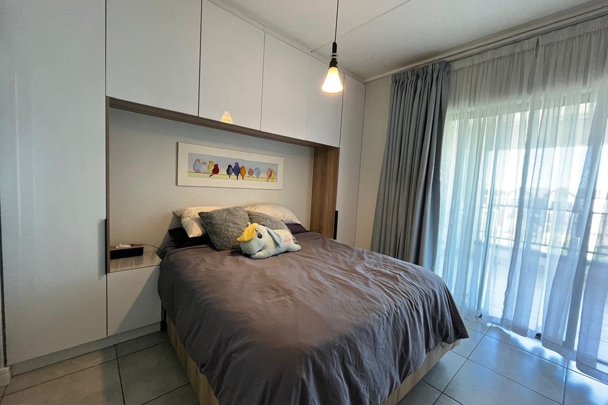 A modern bedroom featuring extensive built-in cabinetry, tiled flooring, and a sliding glass door providing access to an outdoor area.