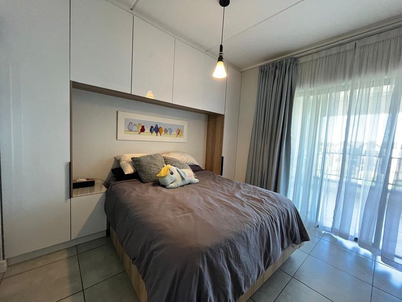 A modern bedroom featuring extensive built-in cabinetry, tiled flooring, and a sliding glass door providing access to an outdoor area.