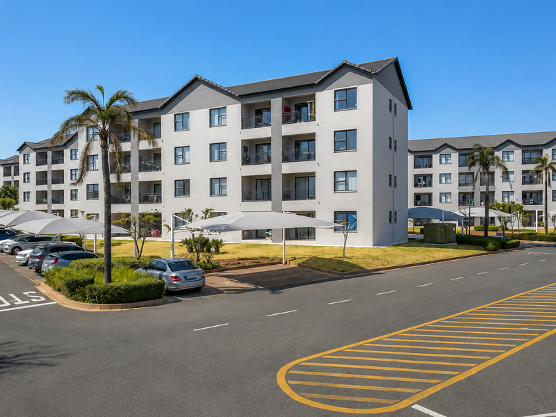 Exterior view of a modern multi-story apartment complex featuring paved parking areas with shade cloth carports and landscaped grounds.