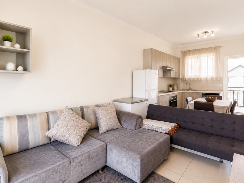 Open-plan living and kitchen area featuring tiled floors, modern cabinetry, built-in appliances, and direct access to a private balcony.