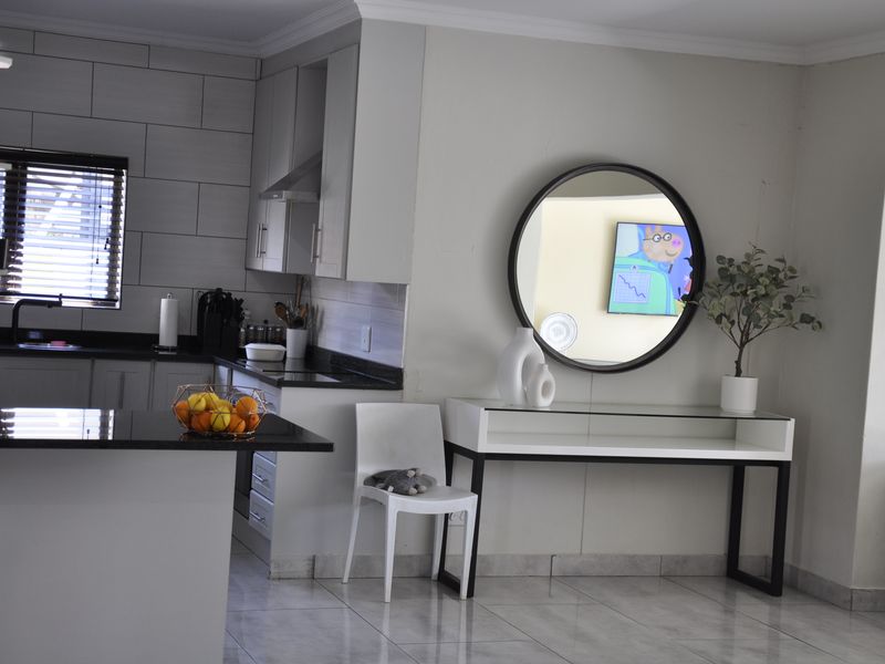 Modern open-plan kitchen featuring sleek cabinetry, granite countertops, and tiled flooring, seamlessly flowing into the adjacent living area.