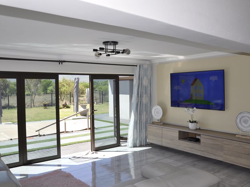 Bright living room featuring large sliding glass doors that open to a patio, tiled flooring, and a modern built-in media console.