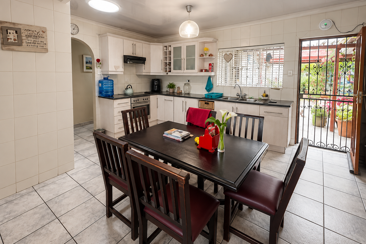 A functional kitchen featuring tiled walls and flooring, built-in cabinetry, a double basin sink, and direct access to an outdoor patio area.