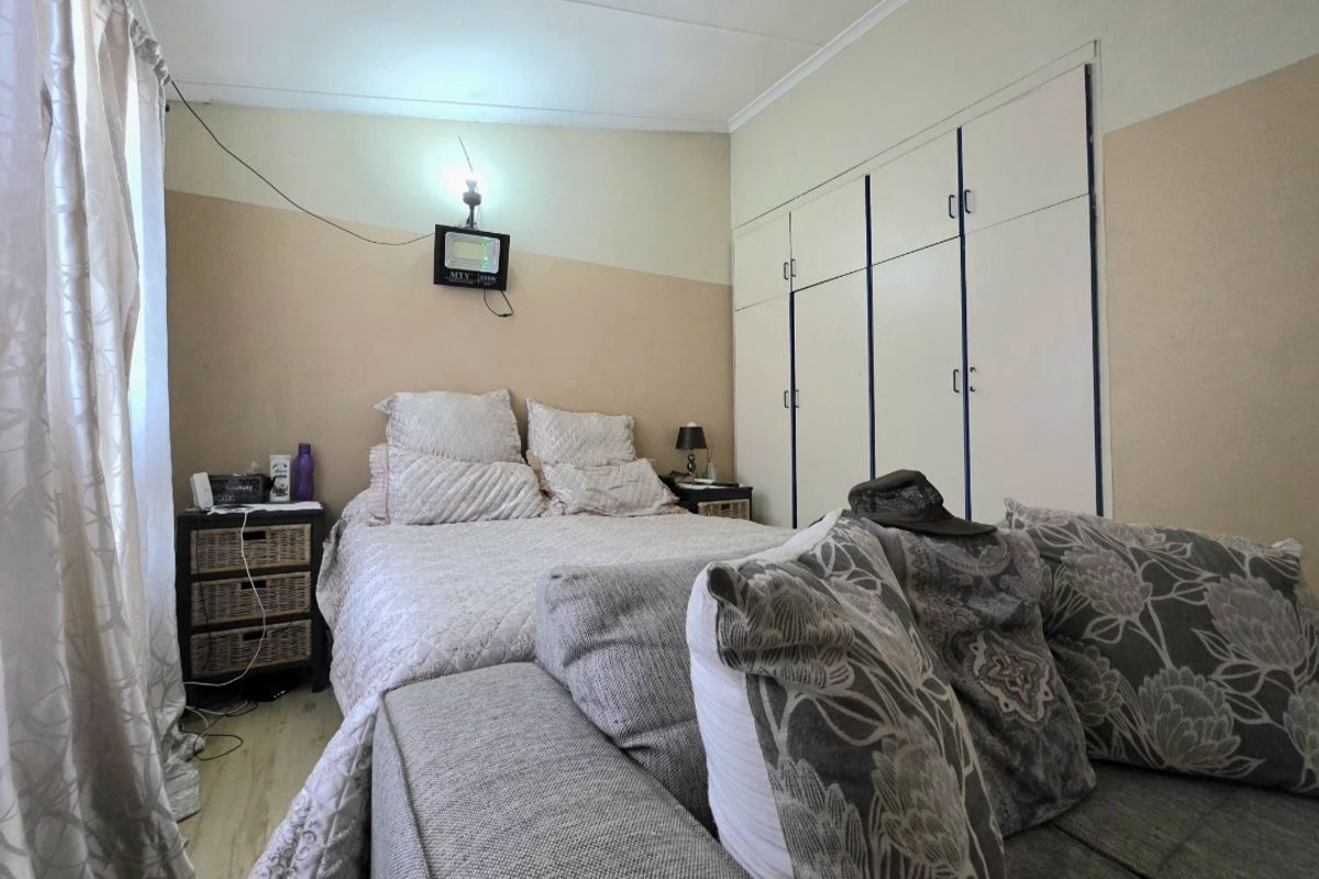 A bedroom featuring built-in cupboards and neutral wall finishes, providing a functional space with potential for cosmetic updates.