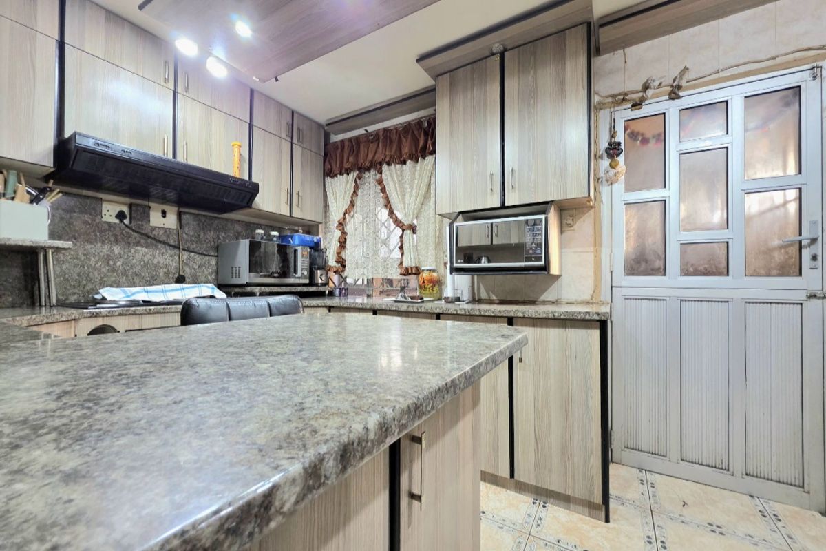 A functional kitchen featuring wood-look laminate cabinetry, granite countertops, an integrated microwave, and a glass-panelled door leading to the exterior.