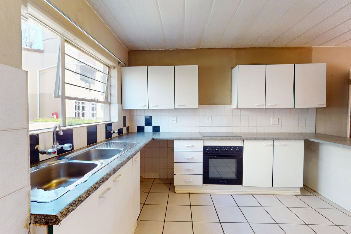 A functional kitchen featuring built-in cabinetry, a double basin sink, and an integrated oven with hob, offering a blank canvas for modern updates.